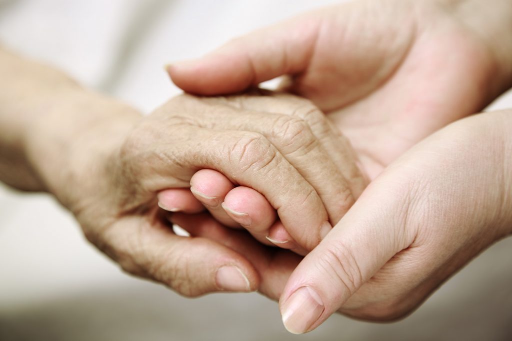 An elderly hand held by young hands