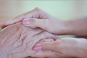 Close up of elderly hands held by younger hands