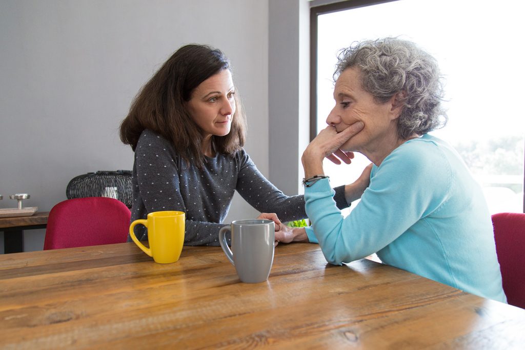 Serious young woman consoling her upset senior mother