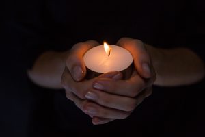 Hands holding candle on black background