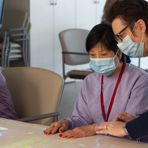 ADP staff member assists client with a game using the Lucynt magic table