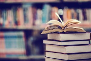 "stack of old books in front of bookshelf"