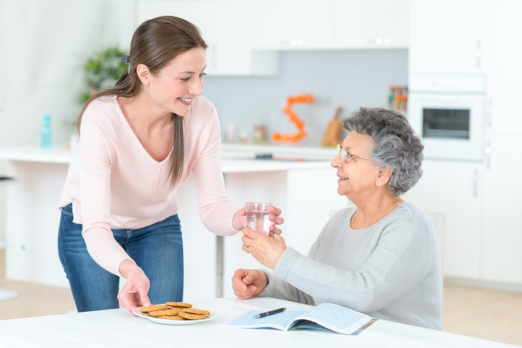 woman handing an older adult a glass of water