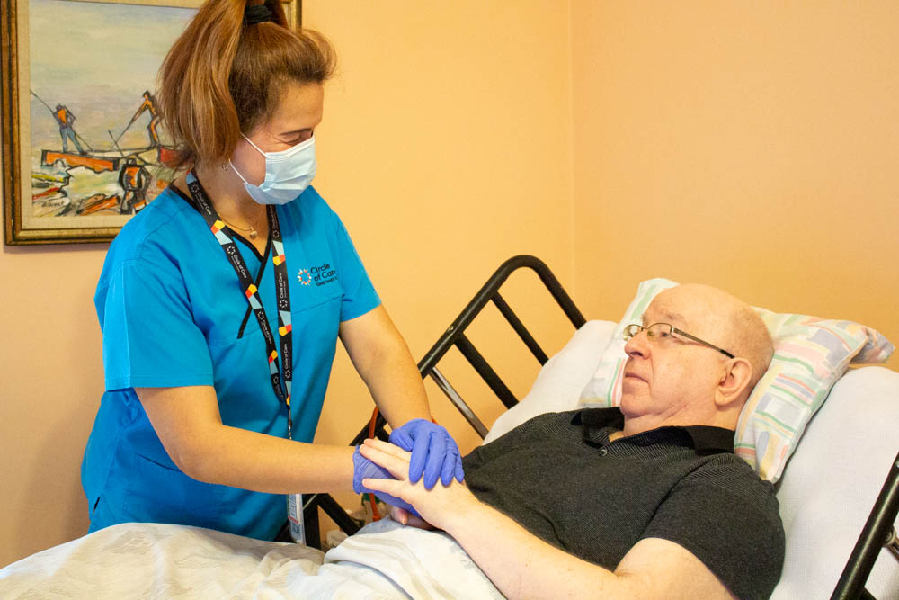 A PSW helps client Dan, who lies on his bed