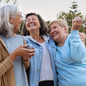 three senior women holding bocce balls and laughing