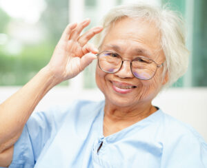 "Senior woman putting eyeglasses on her face close-up photo"