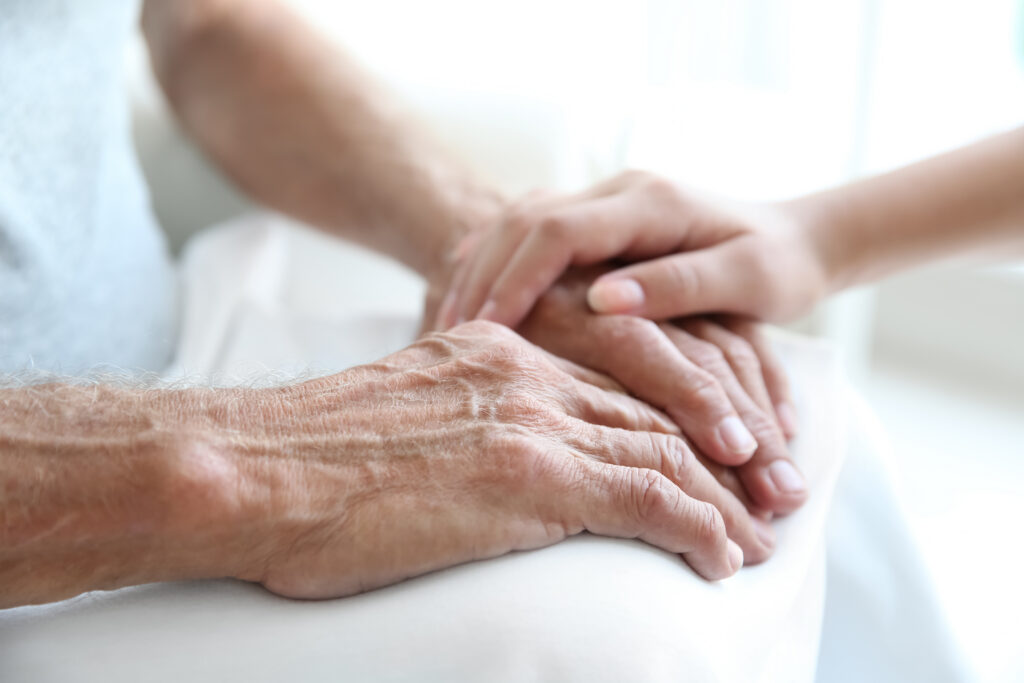 "Close-up photo young person's hand touching senior's hands in support"