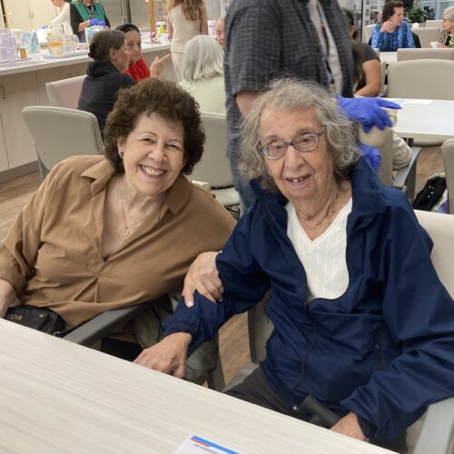 Two seniors sitting together and smiling.