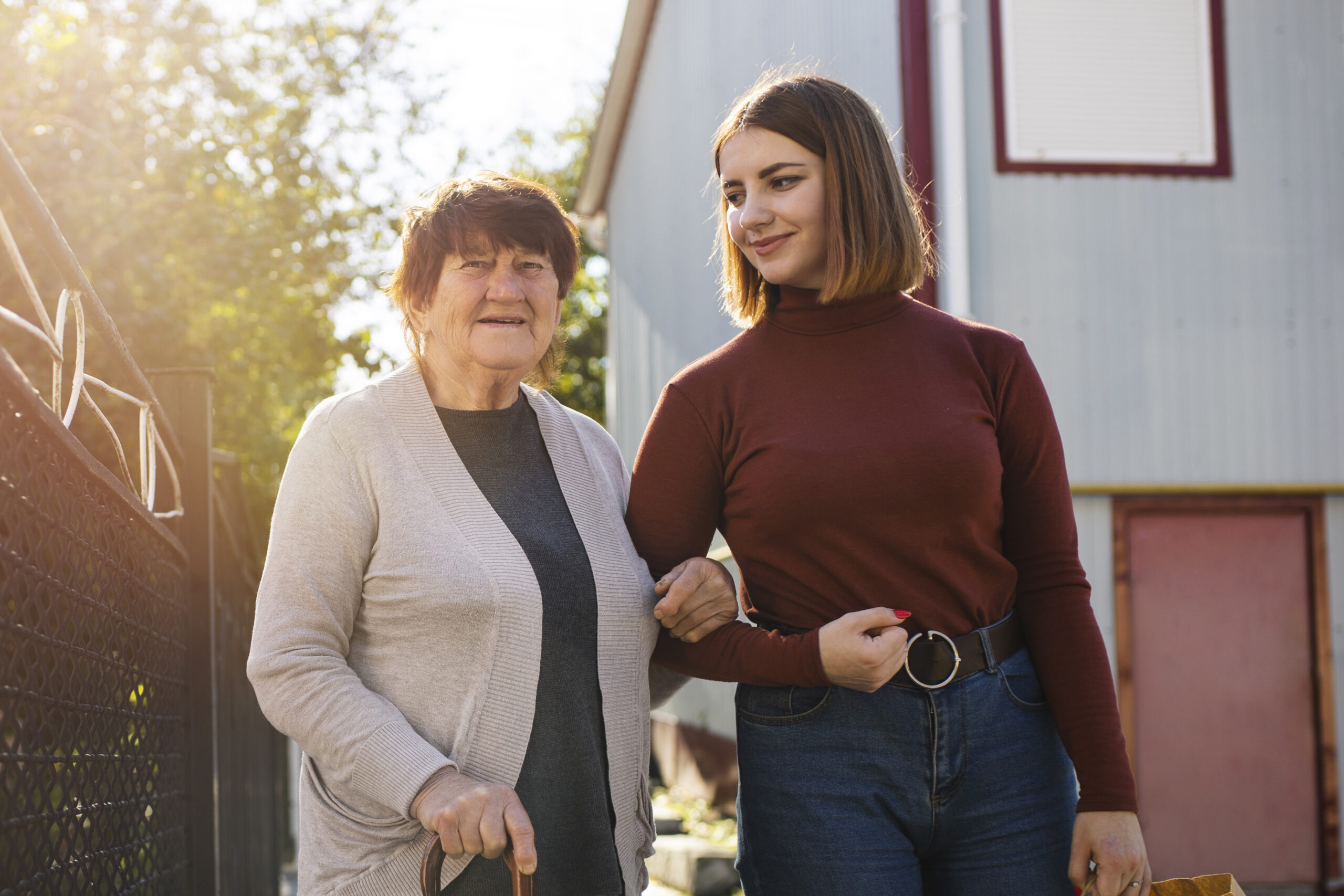 "young woman linking arms with senior woman while walking"