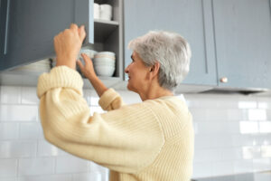 "senior woman reaching for kitchen cupboard"